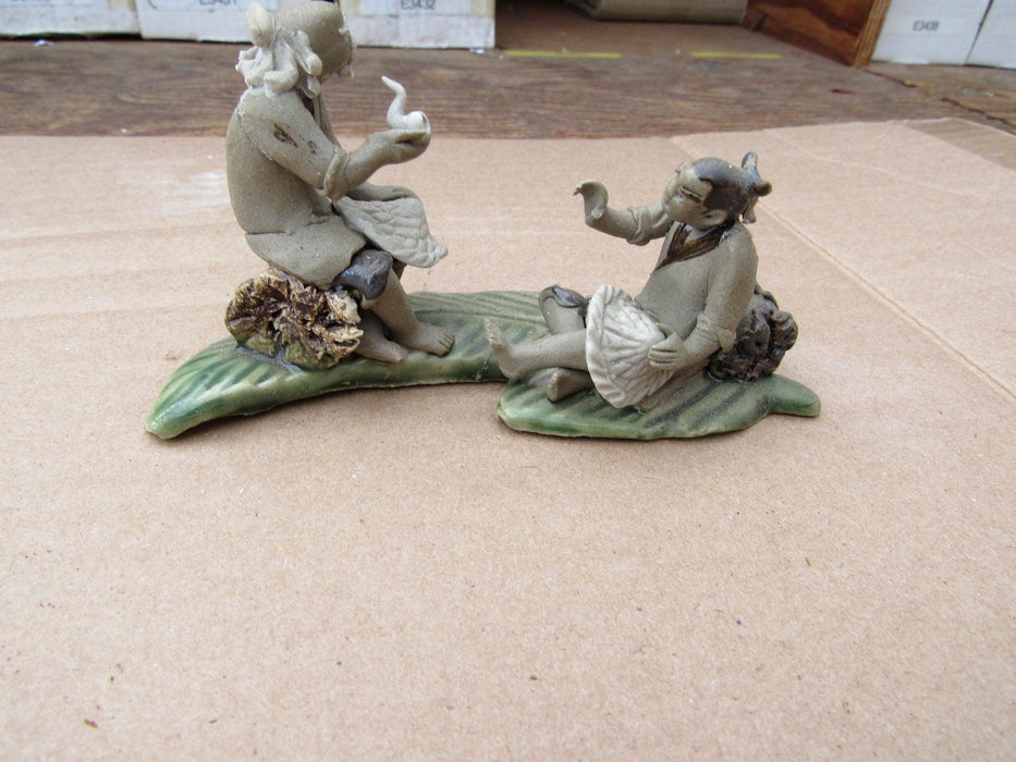 Two Mud Men Smoking On A Leaf Figurine Front